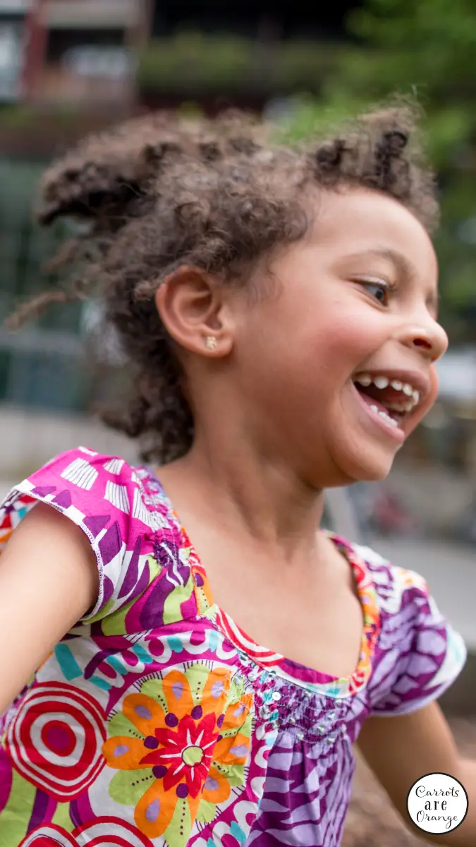 une fille noire souriante en gros plan jouant dehors